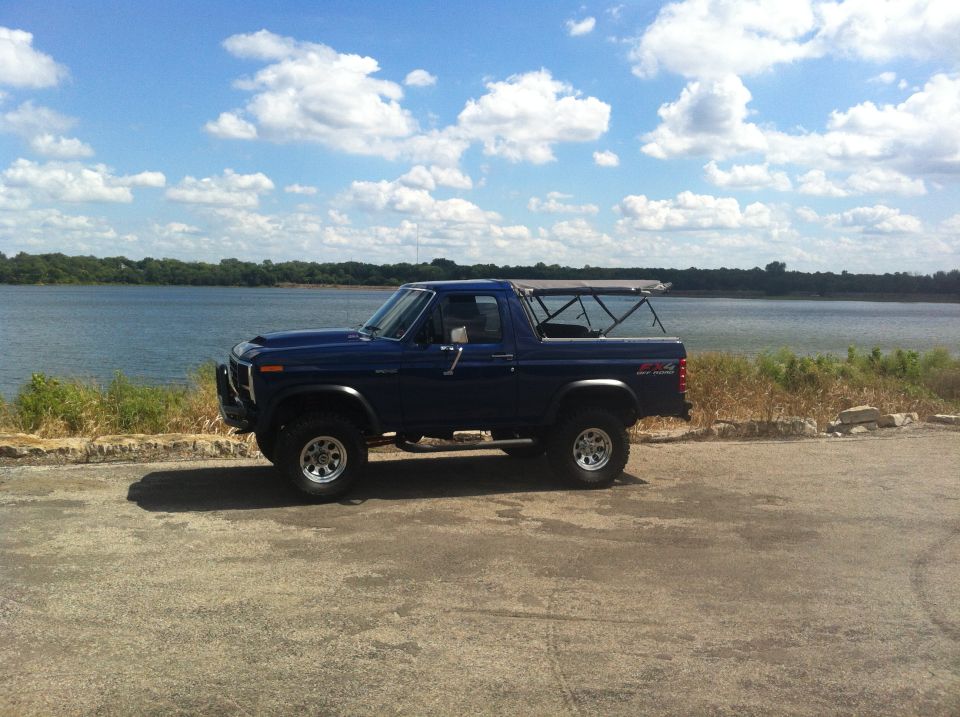 Blue 1982 Ford Bronco parked on asphalt near a lake