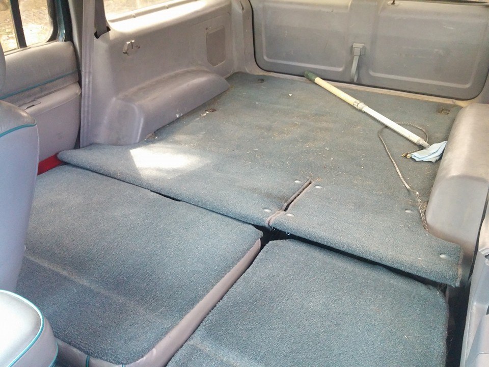 Interior cargo area with folded seats and a broom