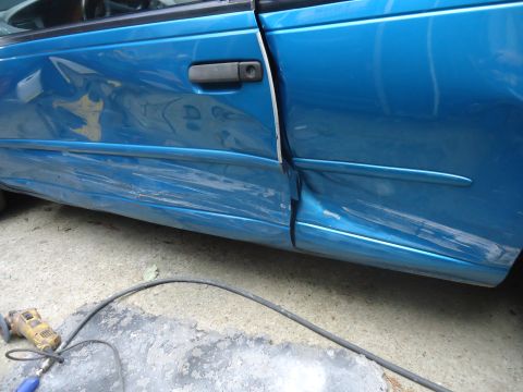 1994 Ford Thunderbird - Side view of a damaged 1994 Ford Thunderbird, with a grinding tool nearby.