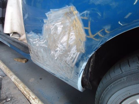 1994 Ford Thunderbird - Bodywork in progress on a blue vehicle, with visible signs of repair and sanding on the lower door panel.