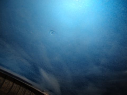 1994 Ford Thunderbird - A small dent is visible on the blue painted body panel of a vehicle.