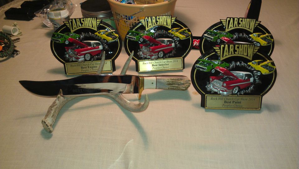 Car show trophies for Best Engine, Best Interior, and Best Paint next to a large knife