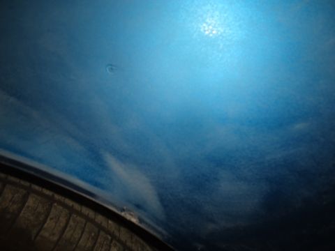 1994 Ford Thunderbird - A dent is visible on the blue painted body panel of a vehicle, with a tire in the lower portion of the frame.