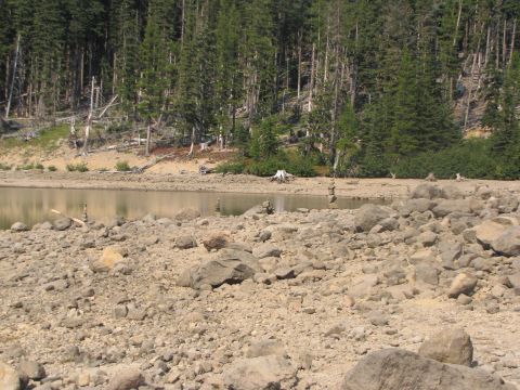 1992 Ford F-150 - Stacked rocks mark the shoreline of a lake surrounded by a dense forest.