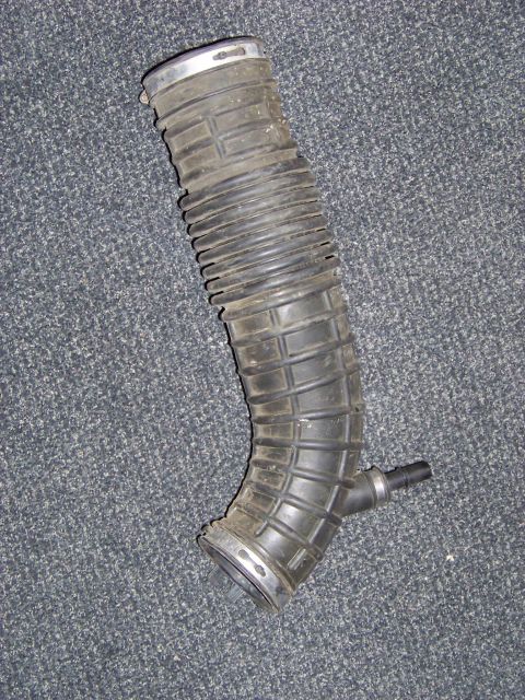 1995 Mercury Grand Marquis - A rubber air intake hose is shown against a carpeted background.