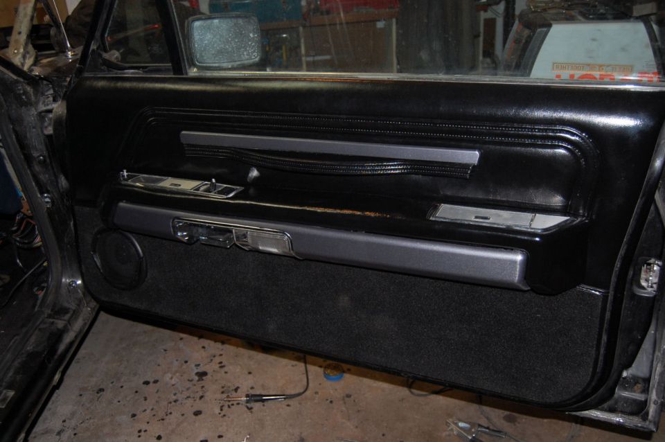 Interior door panel with black vinyl, chrome accents, and speaker grille