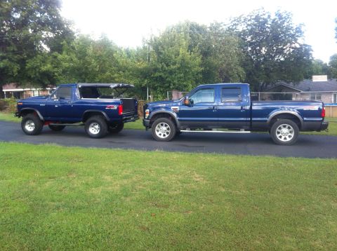 1982 Ford Bronco - A classic blue Ford Bronco is parked next to a modern blue Ford F-Series truck.
