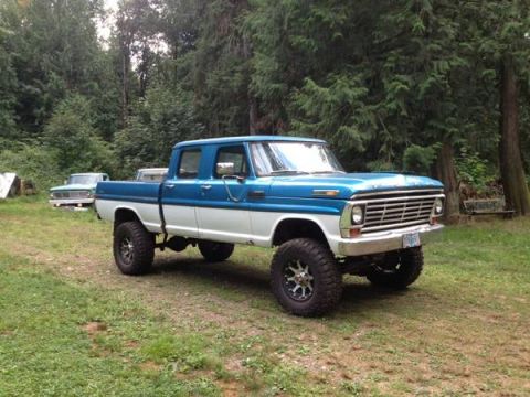 1971 Ford F-250 - A lifted pickup truck with a two-tone paint scheme sits in a wooded area.