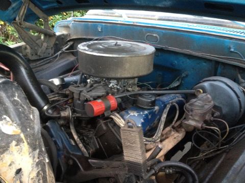 1971 Ford F-250 - The engine bay of a blue 1971 Ford F-250 shows a V8 engine with a prominent air filter and carburetor assembly.