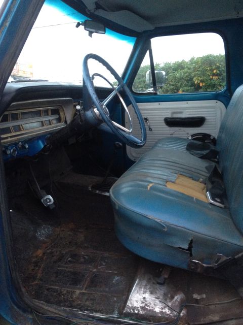 1971 Ford F-250 - The interior of a blue truck shows wear and tear on the seats and dashboard.