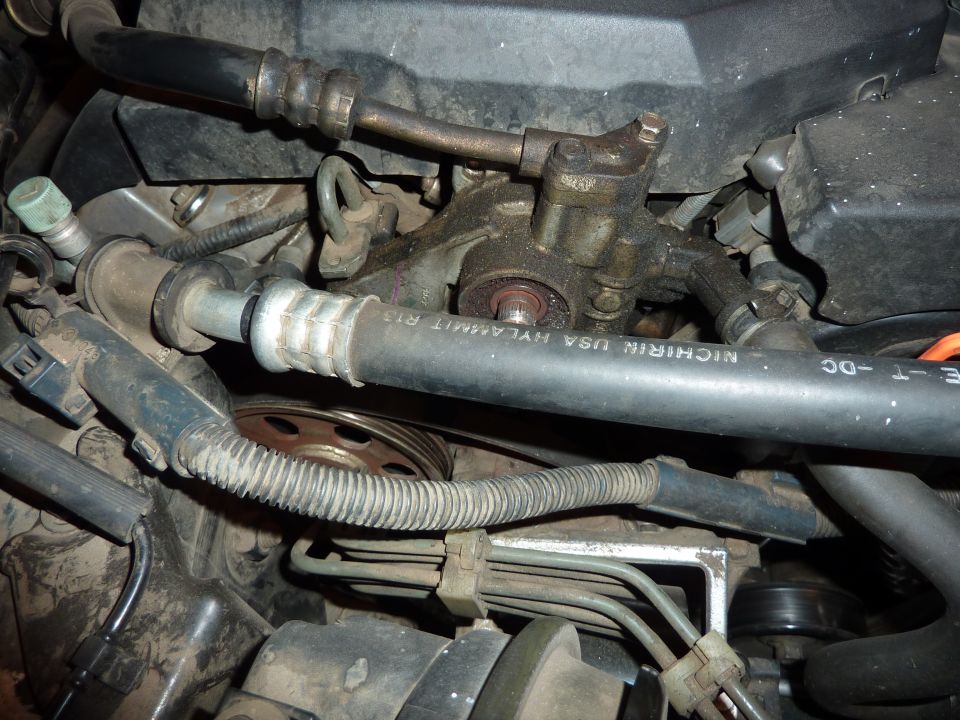 Engine bay close-up of power steering pump with pulley removed, Nichirin hose in foreground