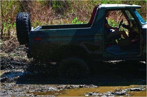 1979 Ford Bronco - A 1978 Ford Bronco navigates a muddy trail, kicking up water and dirt.