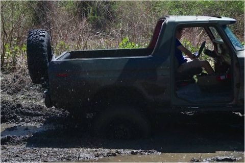 1979 Ford Bronco - This 1979 Ford Bronco navigates a muddy trail, its off-road capability with a rear-mounted spare tire.