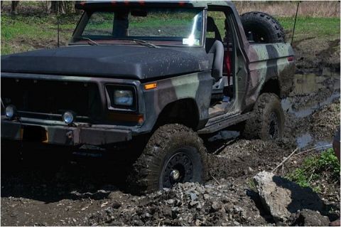 1979 Ford Bronco - A camouflaged Ford Bronco navigates a muddy obstacle course.