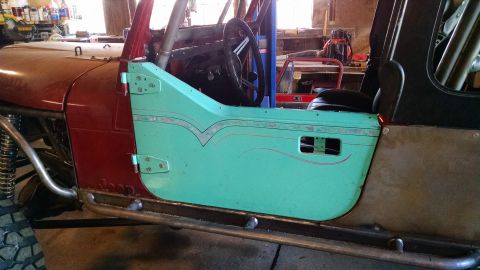 1985 Jeep CJ7 - Side view of a 1985 Jeep CJ7 interior, a teal door with custom pinstriping and a roll cage.