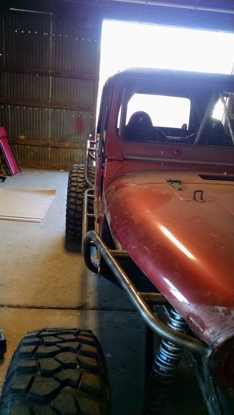 1985 Jeep CJ7 - A custom-built buggy with a roll cage and oversized tires sits in a garage.
