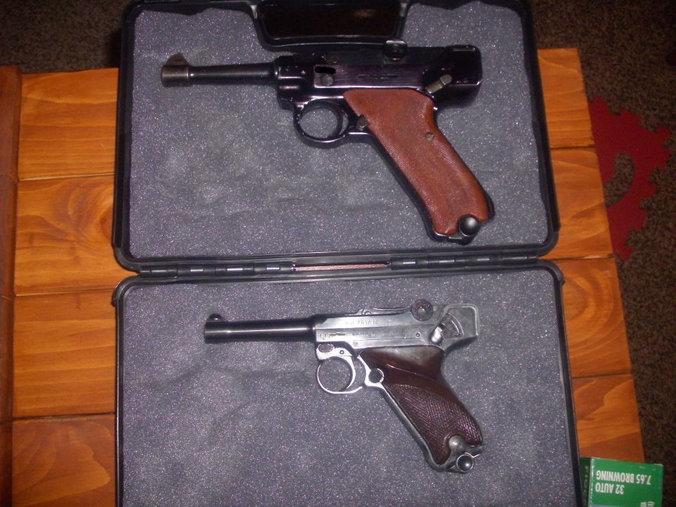 Two Luger pistols in a case, one black with brown grips, one silver with brown grips