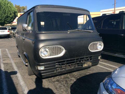 1968 Ford Mustang - A black panel van is parked in a lot, showing its front grille and headlights.