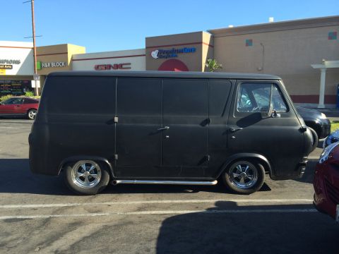 1968 Ford Mustang - A black panel van is parked in a lot with other vehicles visible.
