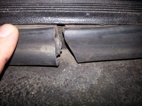 1992 Ford Bronco - A close-up view of a damaged rubber door seal on a vehicle's threshold.