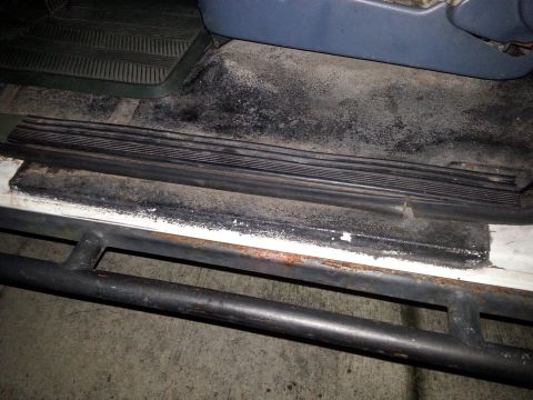 1992 Ford Bronco - Close-up of a vehicle's interior door sill area, showing wear and dirt.