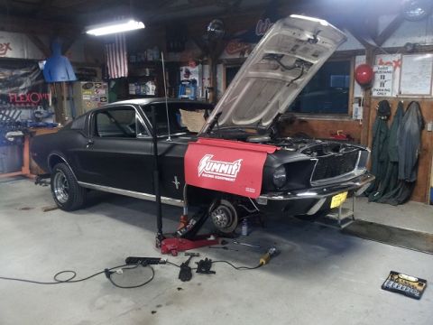 1968 Ford Mustang - A black 1967 Ford Mustang coupe is shown in a garage with its hood open, indicating it is undergoing maintenance or repair.