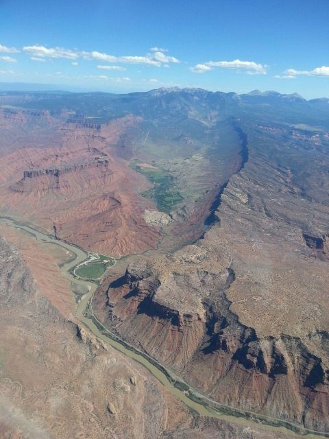 2005 Jeep Wrangler - A river carves through a dramatic canyon landscape under a blue sky with scattered clouds.