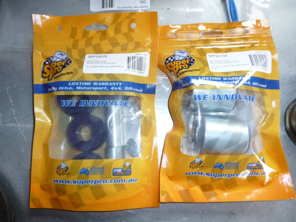 Two Super Pro suspension part packages, one with blue bushings, the other with silver metal parts