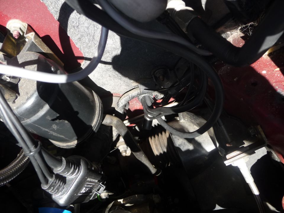 Close-up of engine bay with wires, hoses, and a black ignition coil pack