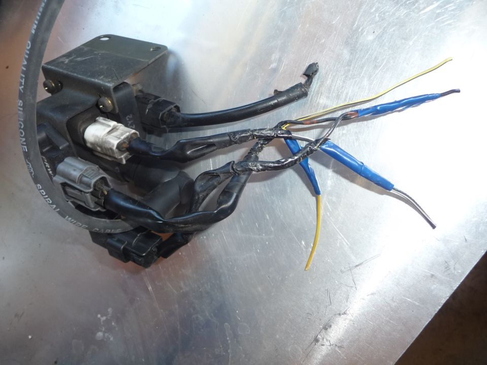 Automotive ignition coil with black housing and multiple wires, some taped with blue electrical tape