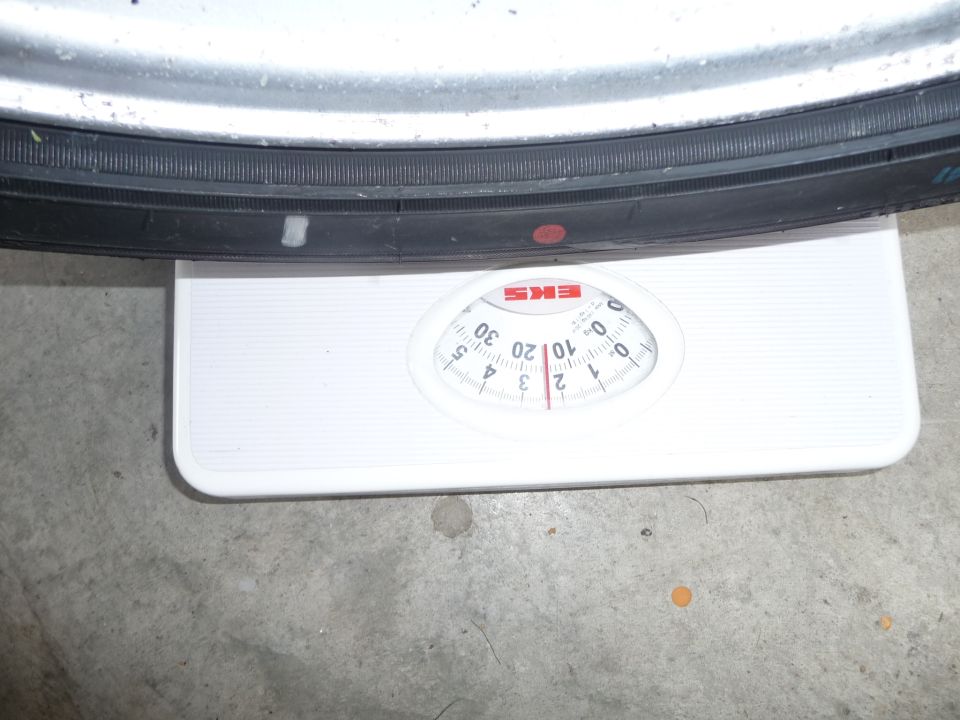 Tire resting on a bathroom scale. Scale shows about 10 pounds
