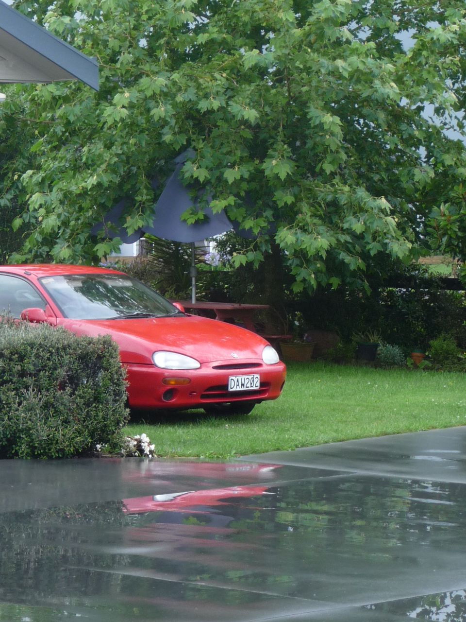 Red 1993 Mazda MX-3 coupe with license plate DAW282 parked on grass