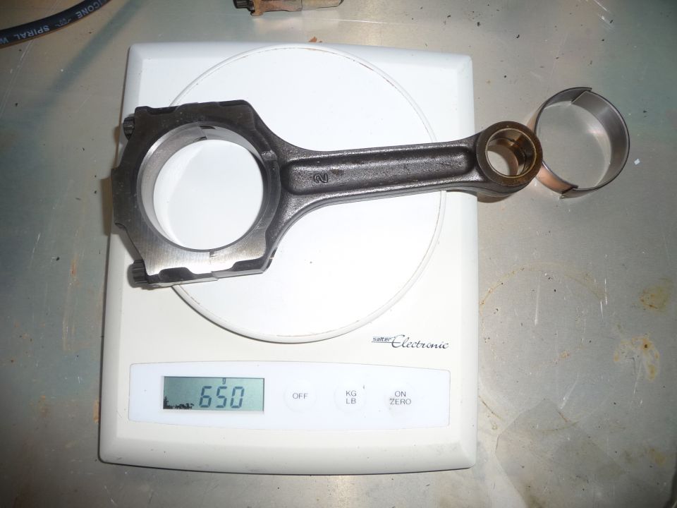 Engine connecting rod and bearing on a digital scale showing 650