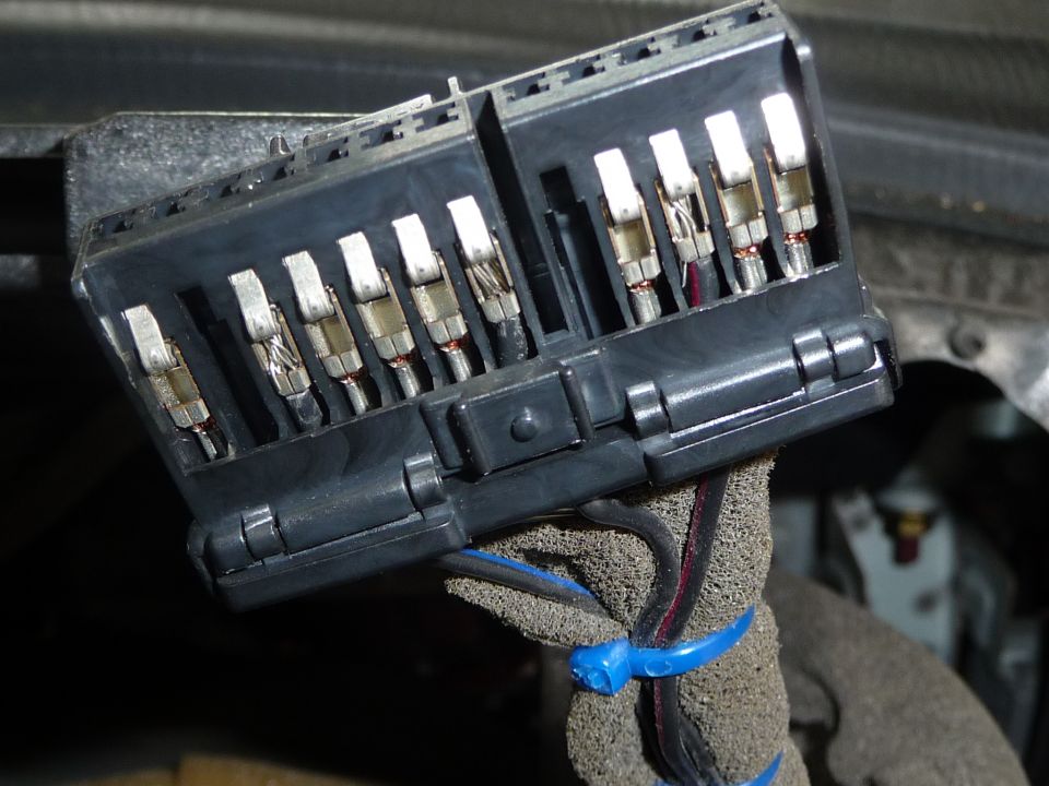 Close-up of a black automotive fuse box with multiple metal connectors visible