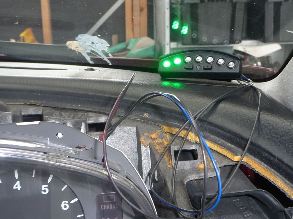 Aftermarket gauge pod with green lights mounted on dashboard, wires visible
