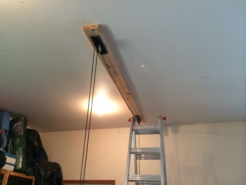 1989 Ford Bronco - A DIY hoist system is installed on the garage ceiling, with a ladder positioned below for access.