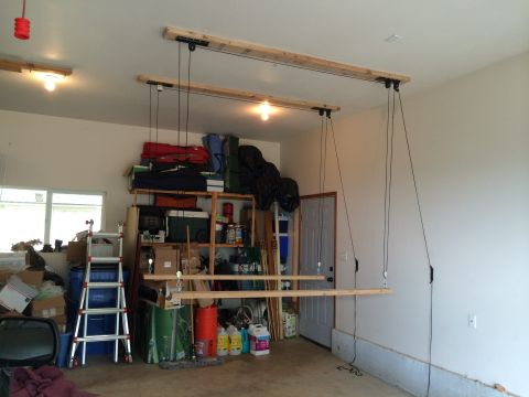 1989 Ford Bronco - A garage interior with a ceiling-mounted hoist system for storage, shelves, and a ladder.
