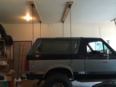 1989 Ford Bronco - Side view of a 1989 Ford Bronco in a garage, with a hoist system installed on the ceiling.