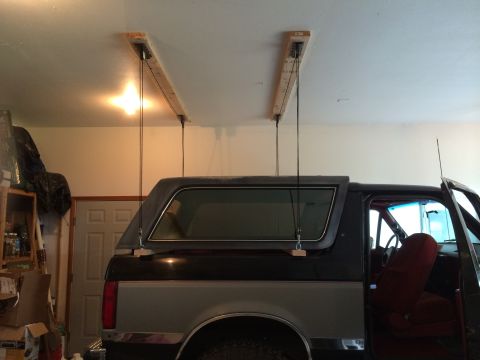 1989 Ford Bronco - The hardtop of a Ford Bronco is hoisted above the vehicle in a garage setting.