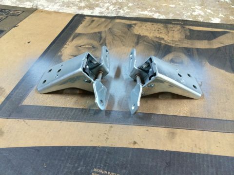 1989 Ford Bronco - A pair of metal door hinges are shown close-up, resting on a patterned cardboard surface.