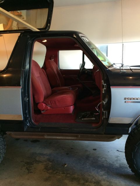 1989 Ford Bronco - Interior view of a 1989 Ford Bronco, showing the red seats and the open driver's side door.