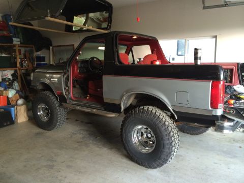 1989 Ford Bronco - This Ford Bronco is parked in a garage with its doors off and the removable top stored above.