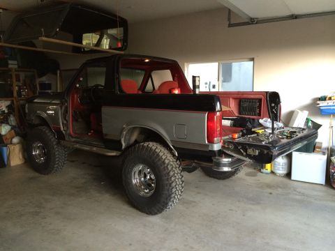 1989 Ford Bronco - A two-tone gray and black Ford Bronco with its tailgate open is parked inside a garage.