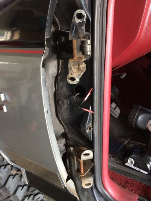 1989 Ford Bronco - Close-up of the door hinge and interior of a gray 1989 Ford Bronco, showing the red dashboard and trim.