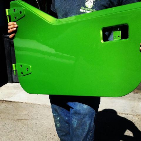 1985 Jeep CJ7 - A person holds up a bright green Jeep door, showing its hinges and a cutout for a window.