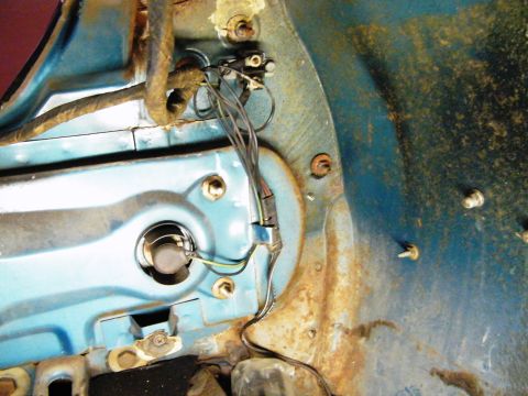 1968 Mercury Cougar - Close-up of the headlight assembly and wiring harness on a 1968 Mercury Cougar, revealing signs of rust and wear.