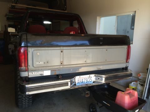 1989 Ford Bronco - The rear of a Ford Bronco is shown in a garage, with a red gas can on a utility cart below the bumper.