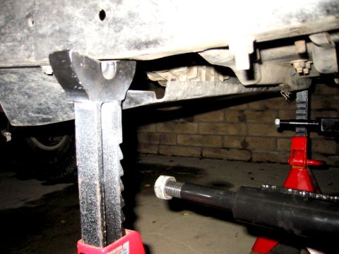 1985 Ford Bronco - The underside of a vehicle is raised on jack stands, revealing its frame and mechanical components.