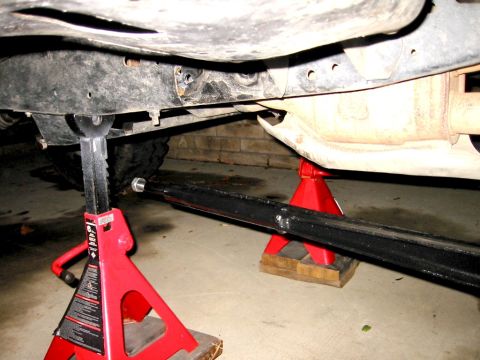 1985 Ford Bronco - The underside of a vehicle is elevated on jack stands for maintenance.