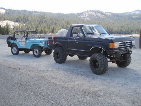 1989 Ford Bronco - Modified 1989 Ford Bronco tows a vintage Jeep CJ through a scenic, mountainous area.